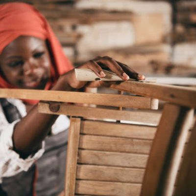 Small business of a young woman. Beautiful young Muslim woman worker in carpenter workroom. Old furniture restoration.